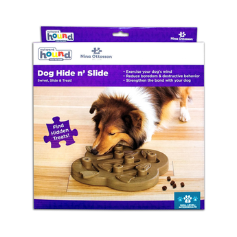 Box packaging for a Nina Ottosson Dog Hide n' Slide toy, featuring a dog on the front of the box looking at the blue puzzle toy.