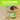 Brown and white collie-type dog playing with the UFO shaped treat dispenser with green central and top parts with main body in grey on a laminated floor. A bright green banner with white text say 'Fun Eating. Shove and chase the toy around to get the treats on the inside'