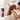 Brown poodle type dog in a bath tub, with a woman holding a shower head over the back of the dog. In the foreground is a black and red bottle of Animology Dogs Body Shampoo.