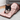 An adult black and white cat sat inside a Battersea Peek-A-Boo Sack in a living room with a grey sofa.