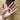 A hand is pictured with a bone shaped treat in the palm, with a dog's nose visibly waiting for the treat, the rest of the face is not visible. The dog is sat on a wooden floor.