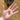 A hand is pictured with a bone shaped treat in the palm, with a dog's nose visibly waiting for the treat, the rest of the face is not visible. The dog is sat on a wooden floor.