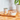 A can of Calibra Life Adult Monoprotein wet cat food sits on a wooden cutting board next to a white bowl filled with the wet food, set on a wooden countertop with a tiled wall and a potted plant in the background.