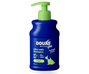 White background with a blue bottle of Douxo Ultra-safe Puppy Shampoo with a green pump.
