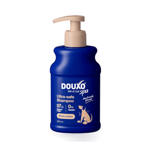 White background with a blue bottle of Douxo Ultra-safe Shed Control Shampoo with a beige pump.