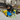 Living room environment with a black and tan small dog with two blue and yellow Happy Pet Minion dog toy with tug ropes at the top and bottom, one large and one small.