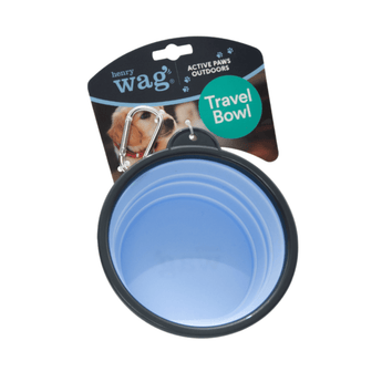 White background a blue Henry Wag dog travel bowls with a black trim attached to a cardboard tag with a silver clip attachment on the tag. Pictured on the tag is a Labrador puppy.