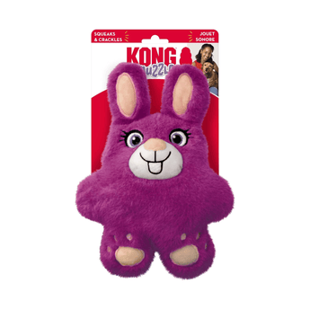 White background with a KONG Snuzzles Bunny dog toy, the main body is made from purple fur body with pink feet and inner ears with stitched features attached to a cardboard backing.