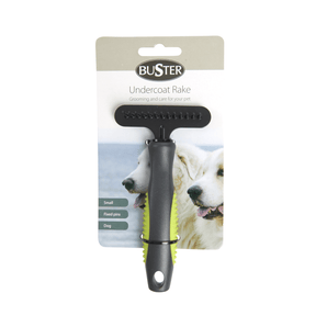 White background with a small black BUSTER Undercoat Rake Brush with fixed pins and green grips on the handle attached to a cardboard backing.