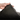 White background with a hand lifting the corner of a bolster-type black dog bed to show the underside.