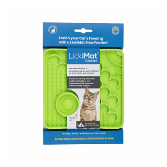 White background with a green square LickiMat Catster slow feeder mat with a scaly and bobbly surface. The Catster mat is in blue and white cardboard packaging with a cat pictured on the packet.