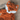 Close up of orange fox shaped dog toy with white chin and stitched detail eyes, brown nose, tags removed, pictured on a wooden floor.