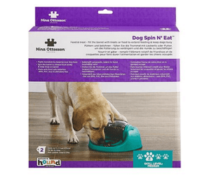 Nina Ottosson Dog Spin N' Eat dog puzzle feeder in its retail packaging, featuring a picture of a golden retriever eating from a teal bowl.