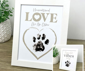Framed print with paw print and 'Unconditional Love Like No Other' text on a wooden surface.