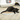 Black kitten with blue collar lying on heart shaped corrugated cardboard scratcher with multicoloured star details around the outside, on a laminate floor.