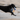 Young black Labrador dog with seagull dog toy with a white body, grey and blue wings and tail and orange beak in it's mouth running on a beach.