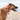 Brown adult dog wearing a hot pink 'Red Dingo' dog collar, on a beach.