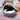 Black and white adult cat curled up in a grey cord and cream plush fabric cat cave pictured in a living room environment.