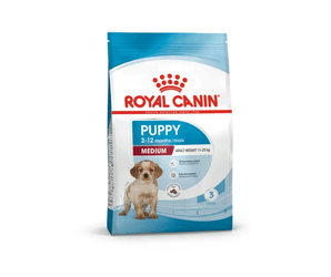 White background with a blue bag of Royal Canin Medium Puppy. Pictured on the bag is a spaniel puppy , text on the bag states '2 - 12 months' and 'Medium, Adult Weight 11-25kg'.