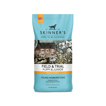 A 15kg bag of Skinner's Field & Trial Puppy & Junior Duck & Rice dog food, designed for young working dogs, featuring a light blue packaging design with a central illustration of a rustic cottage. On a white background.