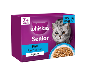 White background with a purple box of Whiskas Fish Favourites on the box is silver tabby cat in front of a bowl on food. Text on the pack reads 'Whiskas, 7+ years, Fish Favourites, in Jelly, 12x85g'.