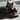 Black cat playing with rainbow shaped cat toy in rainbow colours on a tiled floor.