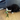A black and white cat playing with an Ancol Greenfinch shaped plush cat toy on a grey string. Pictured in a living room with a grey sofa.