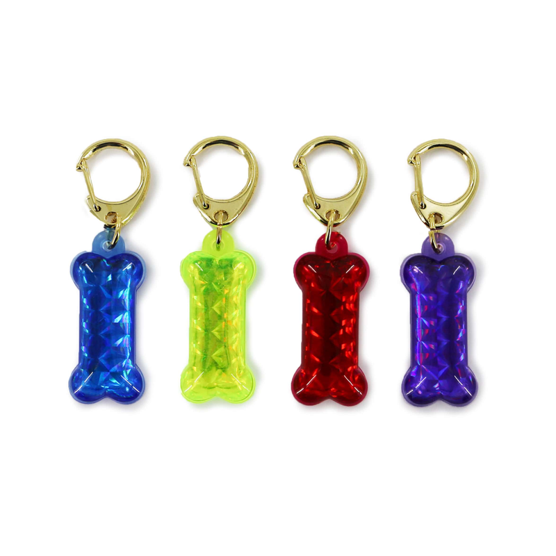 White background with four reflective bone shaped reflective ID tags, in blue, yellow, red and purple. 