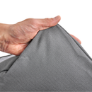 White background with a hand lifting the corner of a bolster-type grey dog bed to show the underside. 