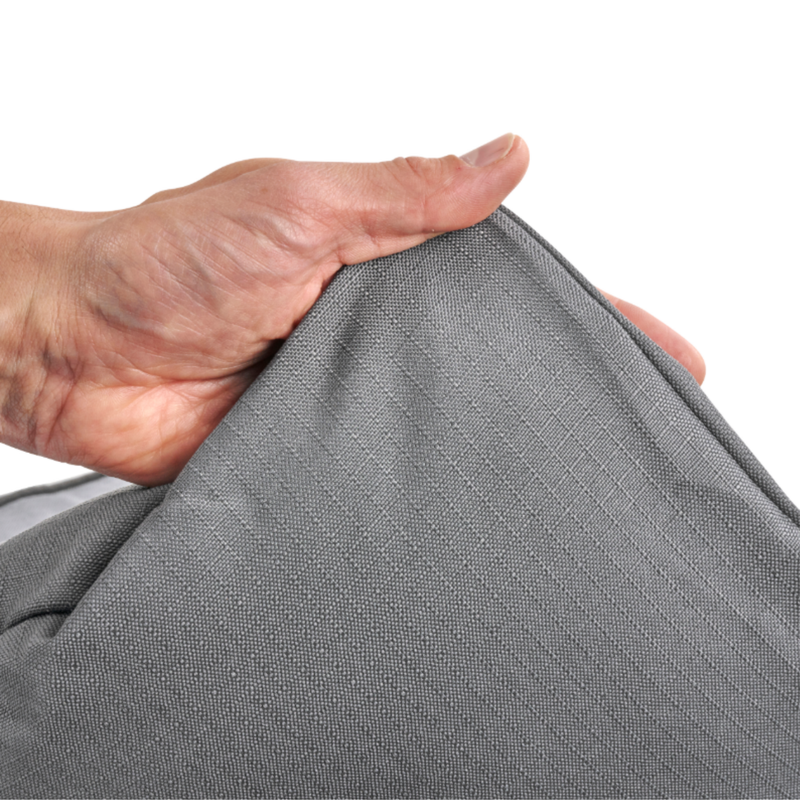 White background with a hand lifting the corner of a bolster-type grey dog bed to show the underside. 