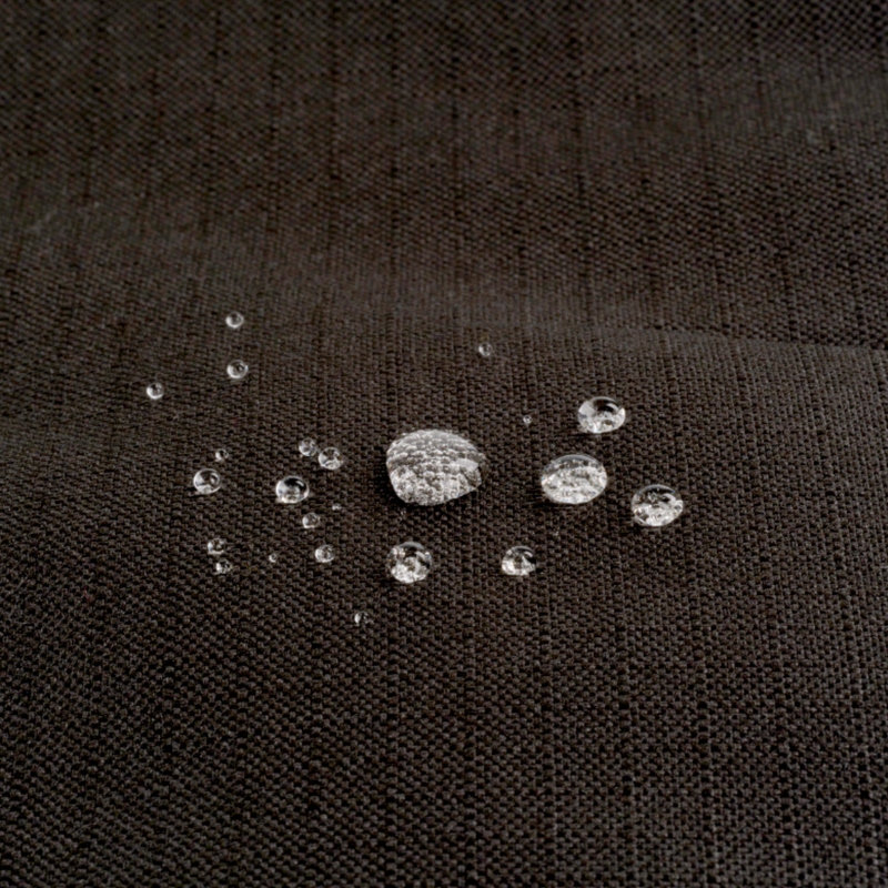 Close up of a Bolster-type black dog bed with water droplets pictured on the waterproof surface. 