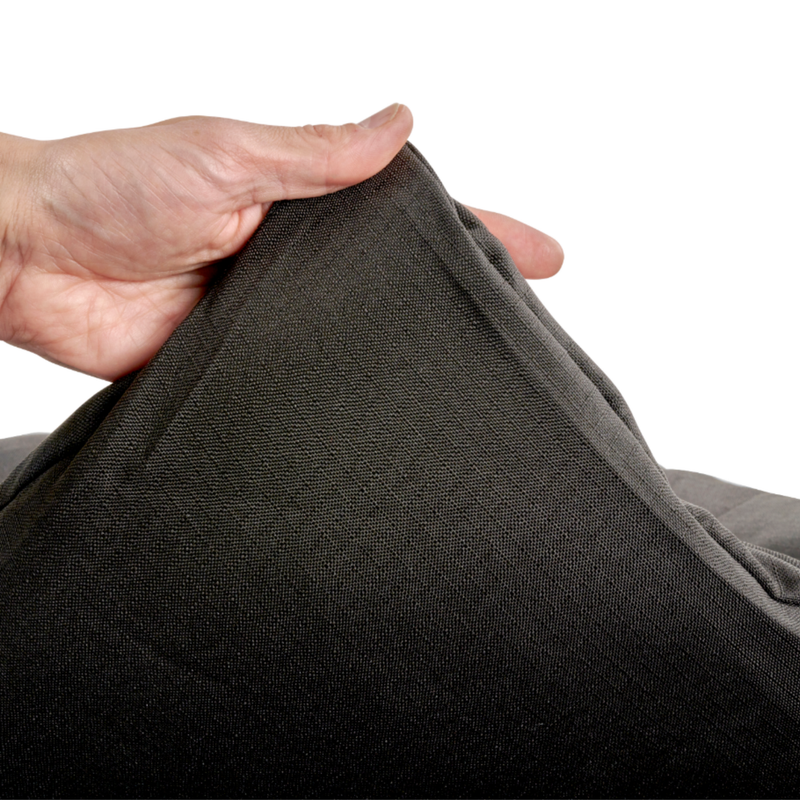 White background with a hand lifting the corner of a bolster-type black dog bed to show the underside. 