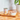 A can of Calibra Life Adult Monoprotein wet cat food sits on a wooden cutting board next to a white bowl filled with the wet food, set on a wooden countertop with a tiled wall and a potted plant in the background.