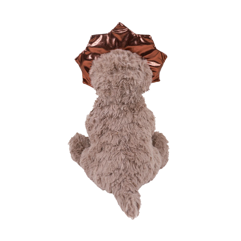 White background with a back view of a brown fluffy dinosaur dog toy with metallic fabric horns and neck frill, attached to a cardboard tag. 