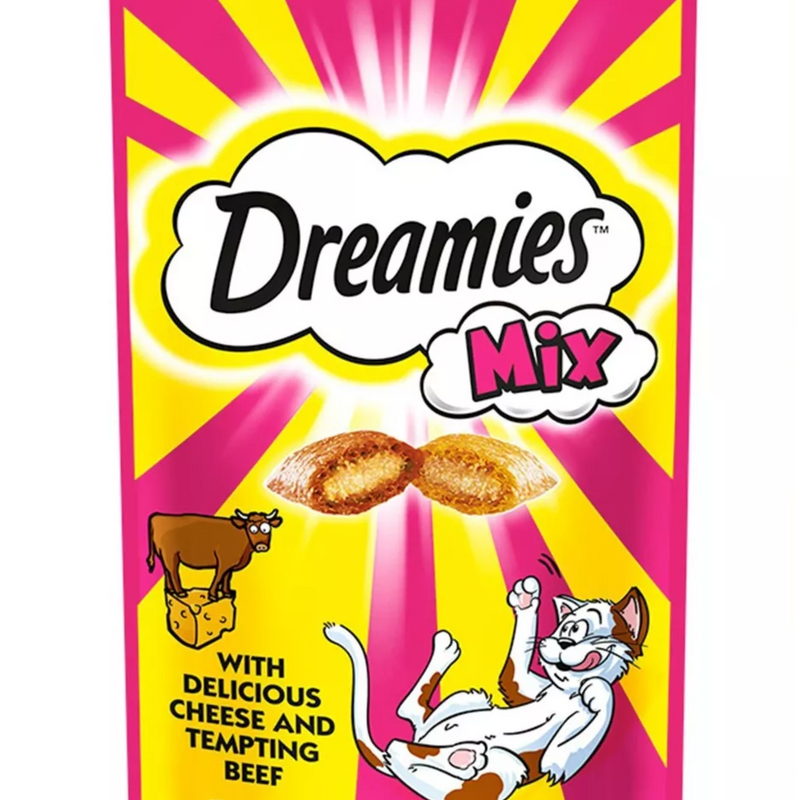 White background with a close up of a pink and yellow packet of Dreamies with Delicious cheese and Tempting Beef pictured. On the packet is an illustrated cartoon cat on it's back with an image of the treats above it and an illustrated fish. Text on the pack reads 'Dreamies, soft inside, crunchy outside, with Delicious cheese and Tempting Beef.' 