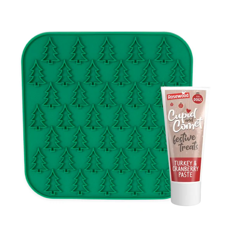 White background with a green lickmat with Christmas trees motif with a tube of Turkey and Cranberry paste next to it. 
