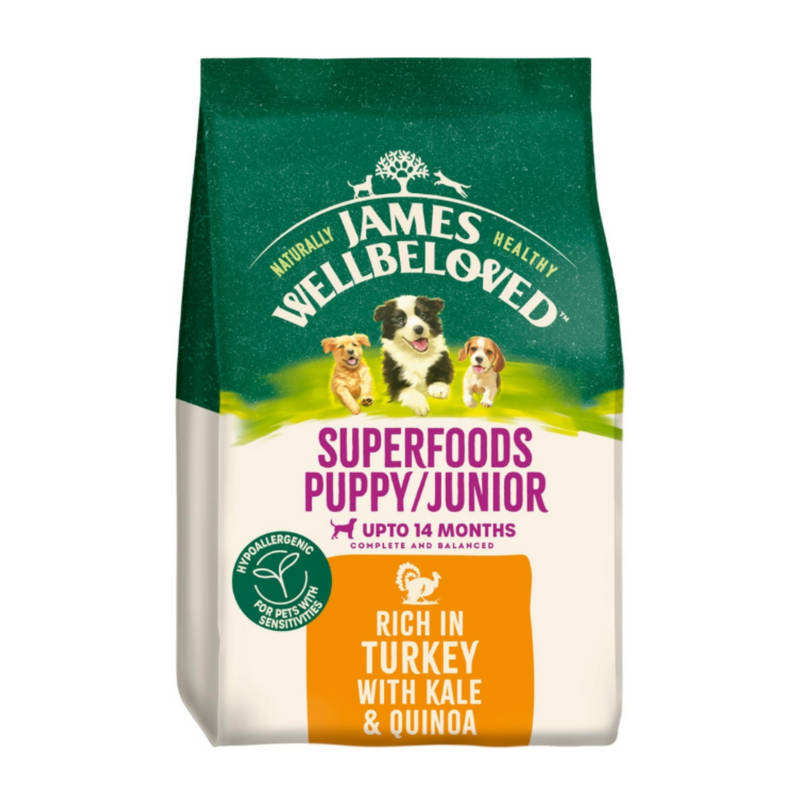 White background with a bag of James Wellbeloved Superfoods Turkey, Kale and Quinoa. Packaging is green and cream with 3 puppies pictured, with text 'Superfoods Puppy/Junior, Upto 14months, Rich in Turkey, Kale & Quinoa'. 