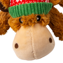 A close up of a Brown fluffy reindeer dog toy with dark brown fabric antlers wearing a red festive patterned hat and a green scarf, pictured on a white background. 