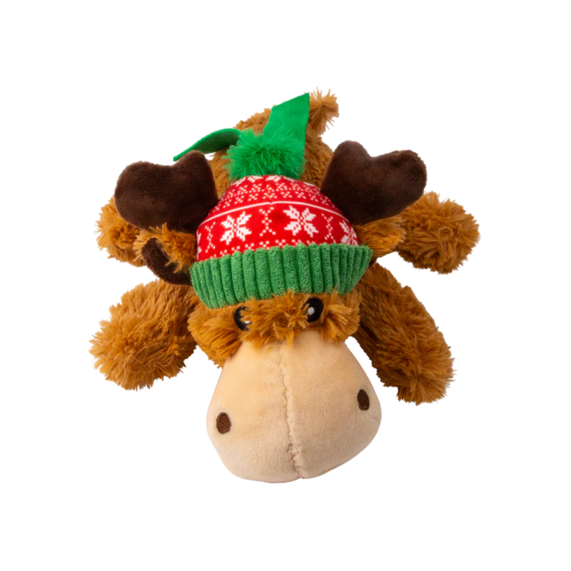 A front view of a Brown fluffy reindeer dog toy with dark brown fabric antlers wearing a red festive patterned hat and a green scarf, pictured on a white background. 