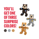 White background with three KONG plush teddy bear dog toys one dark brown, one grey and one light brown, each with patchwork patches. Red text to the left states 'You'll get one of three surprise colours!' 