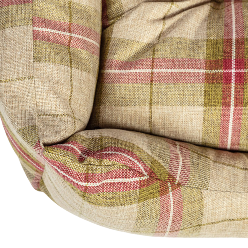 Close up of corner of a plaid green, red and cream fabric dog bed. 