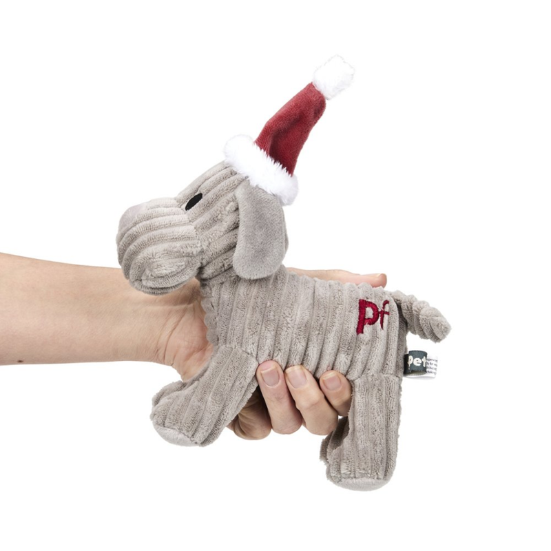 Hand holding a grey dog dog toy made from soft cord effect fleece material with red 'PF' stitched on hip, wearing a red Christmas hat, pictured on a white background. 