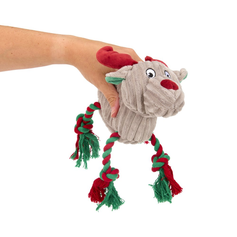 Hand holding grey reindeer dog toy with green and red twisted rope for legs and red fabric antlers on a white background. 