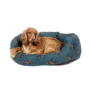 Golden Cocker Spaniel lying in a bolster-type blue dog bed with illustrated stags pictured on a white background. 