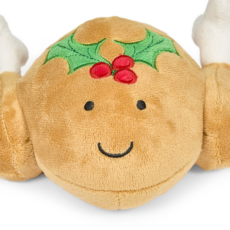 White background with a close up view of a plush dog toy roast turkey with a holly stitched on the top and stitched eyes and smile.