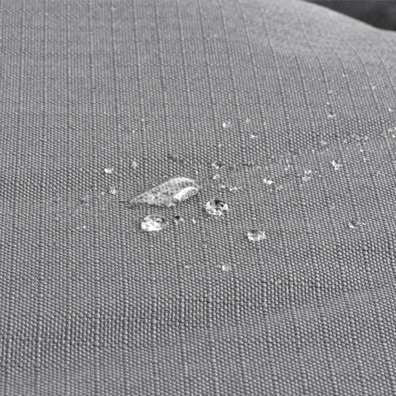 Close up of a Bolster-type grey dog bed with water droplets pictured on the waterproof surface. 