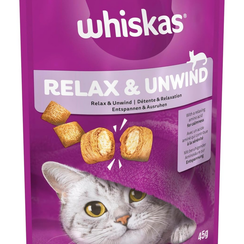 White background with a close up of a purple packet of Whiskas Relax & Unwind Treats, on the packet is silver tabby cat's face under a purple blanket. Text on the pack reads 'Whiskas Relax & Unwind, with a relaxing amino acid for calmness.' 