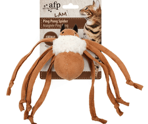 Brown spider toy with a white wool body backed onto packaging with a tabby cat pictured on it, all on a white background. 