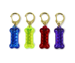 White background with four reflective bone shaped reflective ID tags, in blue, yellow, red and purple. 