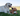 Yellow Labrador dog lying on grass with an Ancol Heritage plush toy deer, made of soft brown and white fabric with black hooves and ears, between its paws